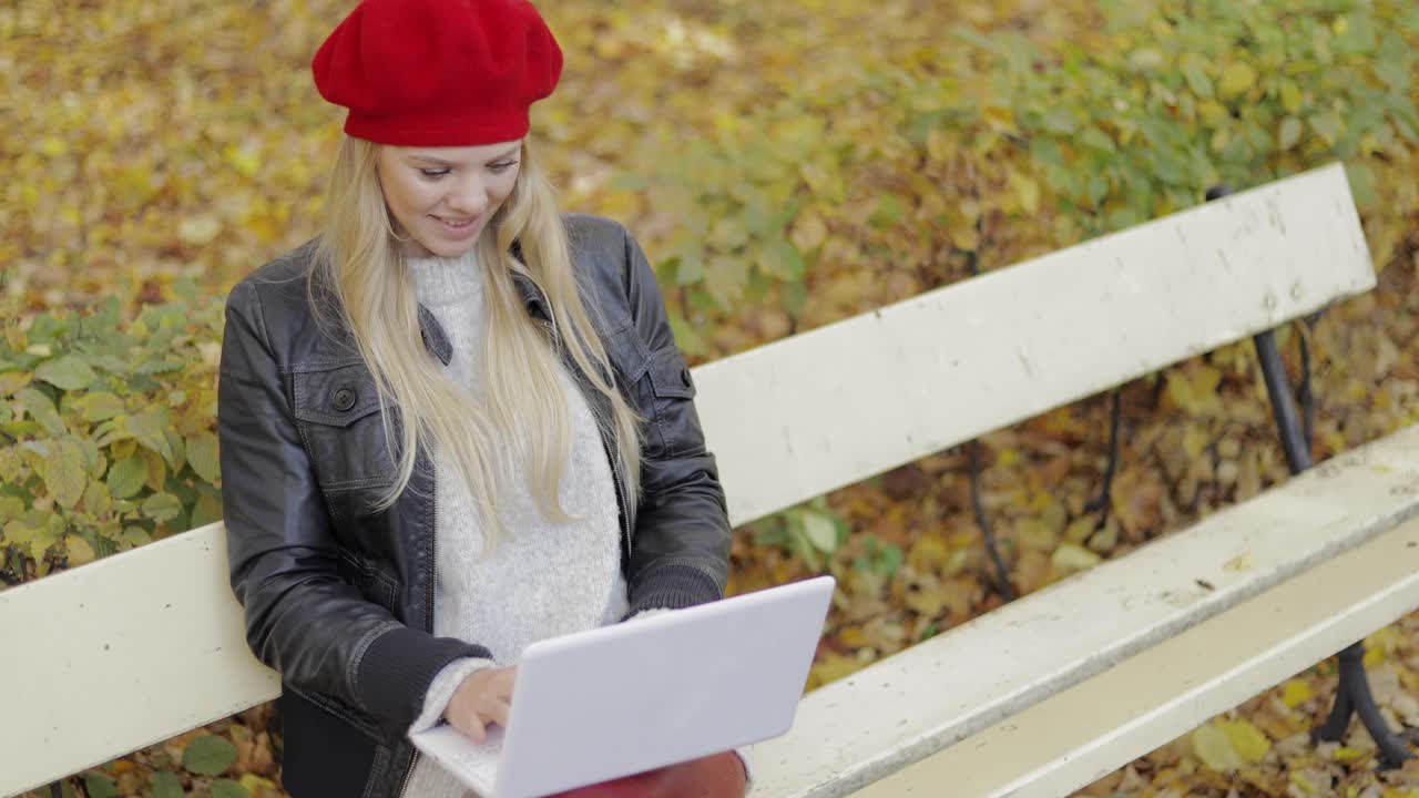 Bella donna che usa il laptop in un parco autunnale