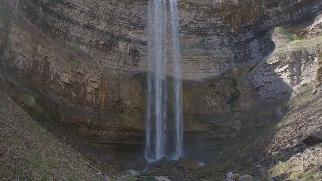 alta cascada que desciende por un acantilado rocoso en una piscina serena debajo, rodeada de naturaleza