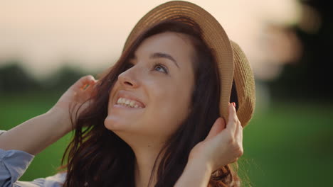 smiling woman wearing straw hat outdoors. portrait of joyful lady in park