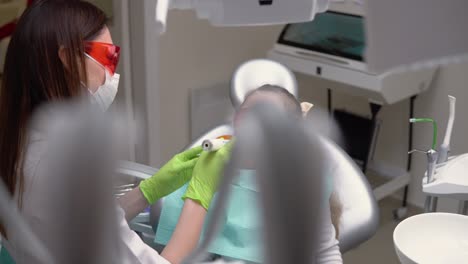 little cute girl at dentist clinic gets dental treatment to fill a cavity in a tooth. dental restoration and material polymerization with uv light. shot in 4k