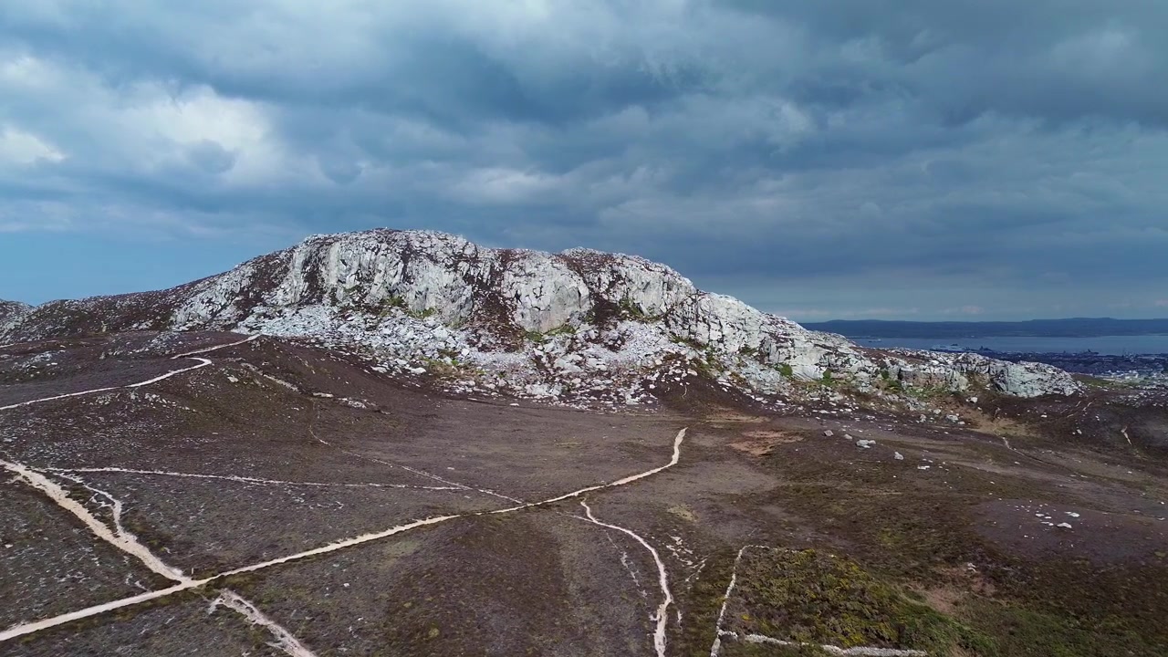 Vista aérea da montanha Holyhead sob céu nublado, mostrando trilha de caminhada, cordilheira da ilha galesa e paisagem marítima.