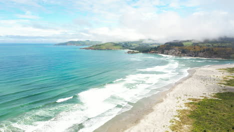 playas exóticas y picos montañosos nublados en nueva zelanda, vista aérea