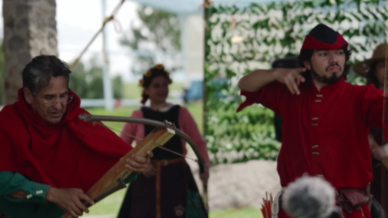 Medieval reenactors with bows and crossbows in an archery demonstration during a festival event