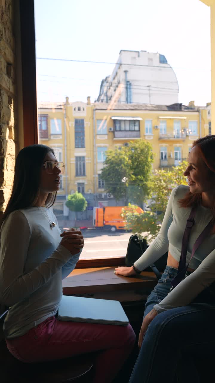 dos mujeres teniendo una conversación en una ventana de un café