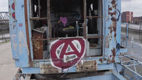 zoom in of abandoned rusty industrial crane with destroyed details and colorful graffiti on chair inside cabin