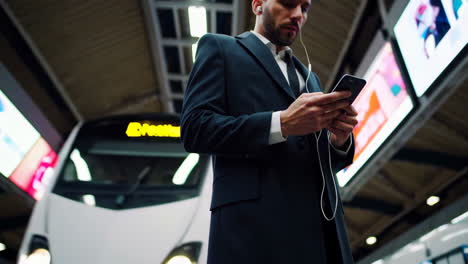 man on a subway platform using his phone