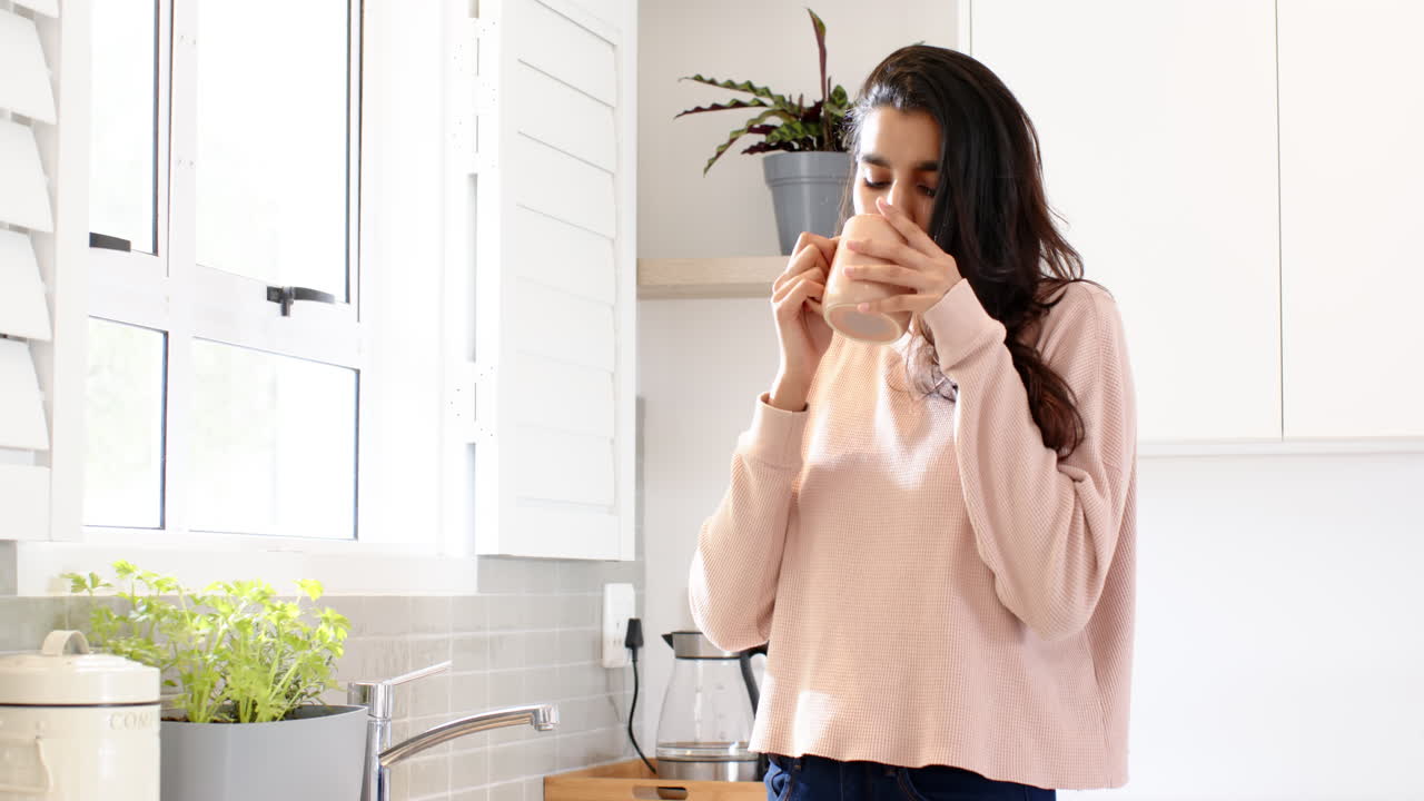 Woman enjoying warm drink in cozy kitchen, savoring peaceful morning moment