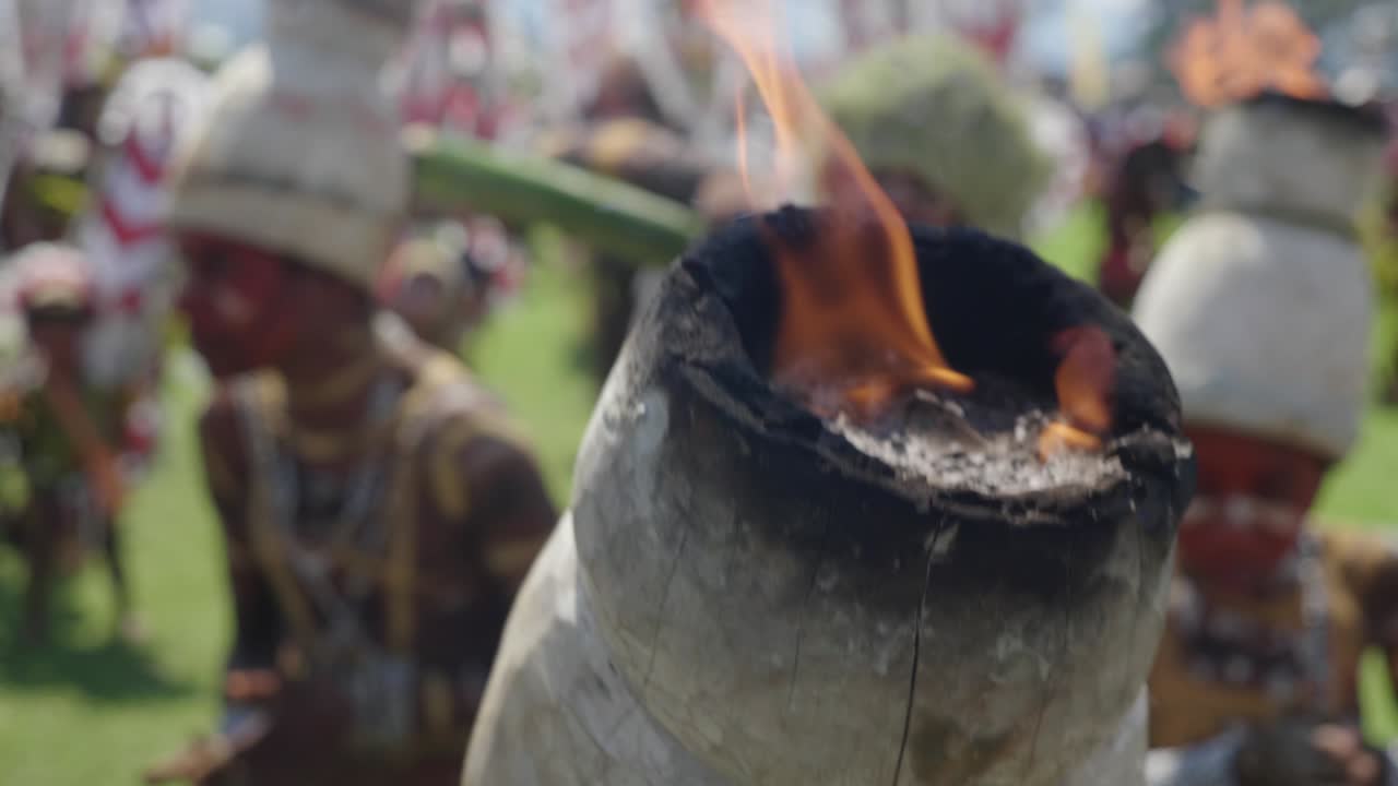 en primer plano, el tocado tribal en llamas en el festival de goroka, la danza tribal en el fondo.