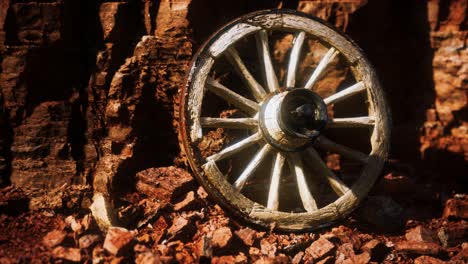 old wooden cart wheel on stone rocks