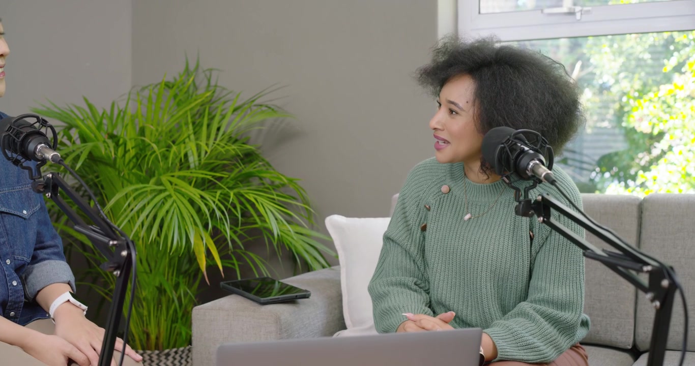 Asian and African American women in denim, green sweater left woman starting chat over mics filming