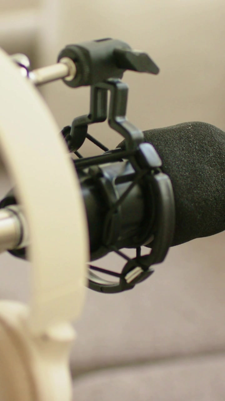 Vertical video: Pulling focus camera shifting right at home studio, revealing mic foam, shock mount