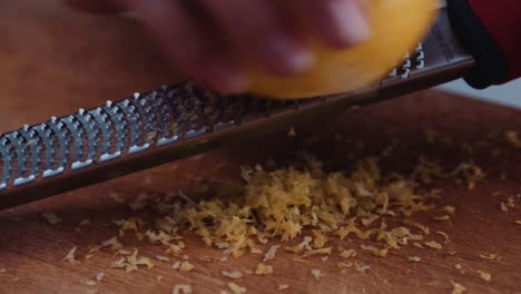 person zesting a lemon - scraping the outer colored part of the peel of a lemon