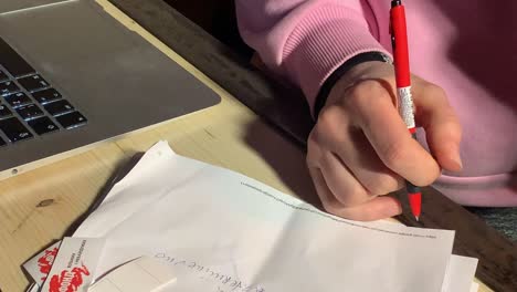 woman taking notes using a pen on her notepad next to a laptop keyboard