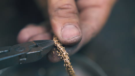 goldsmith cuts leftovers from chain with pliers close view