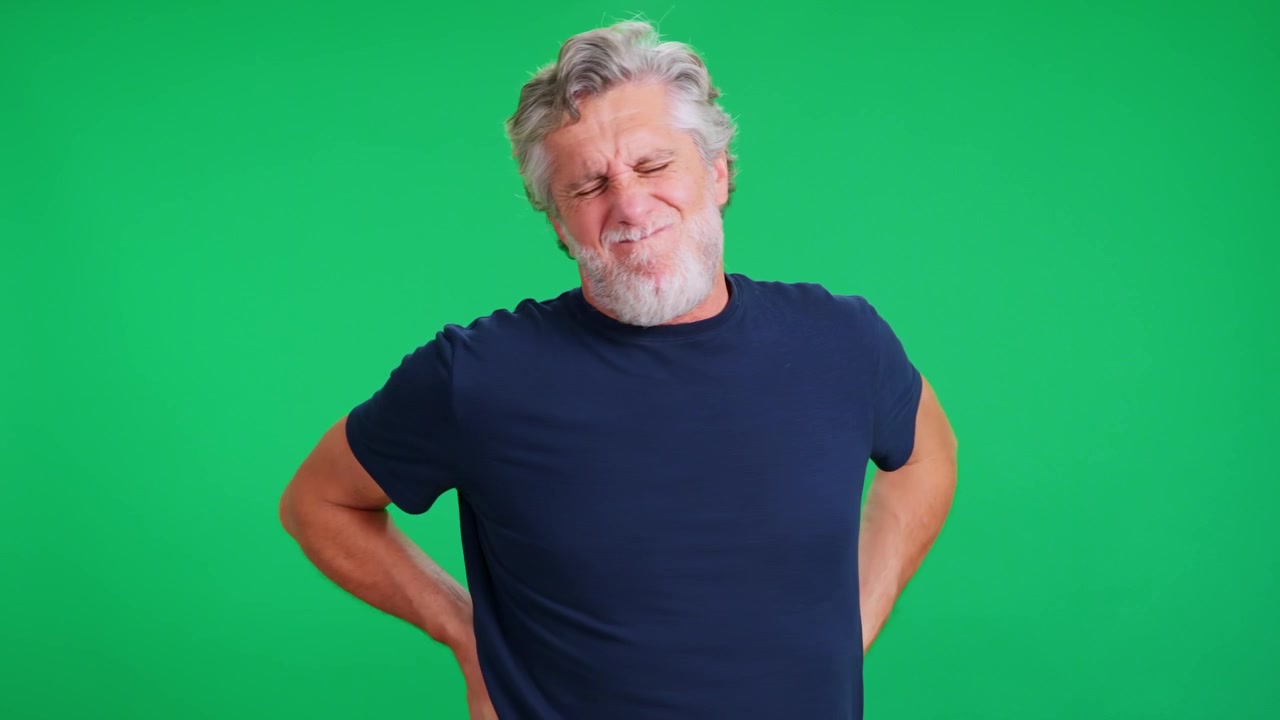 Senior man with back pain on green screen