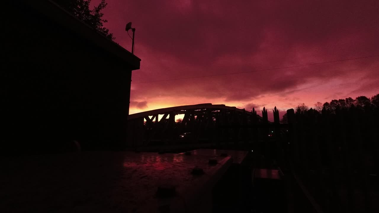 amanecer rojo cielo nublado lapso de tiempo pasando por encima de la silueta del puente del canal arqueado