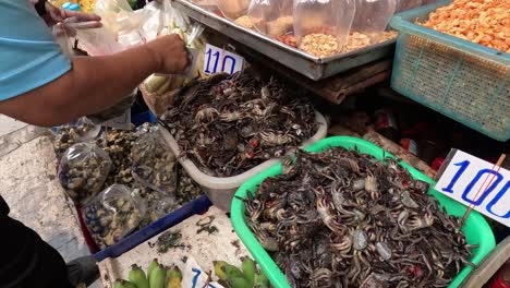 persona organizando cangrejos en un mercado callejero