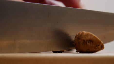 Hand-slices-small-mushrooms-on-cutting-board