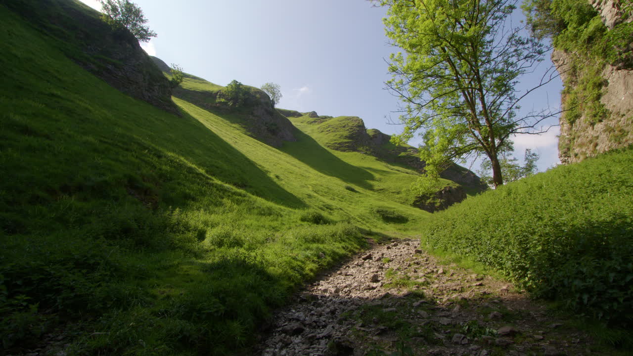 Sentiero roccioso che si snoda attraverso un paesaggio di valle verde.