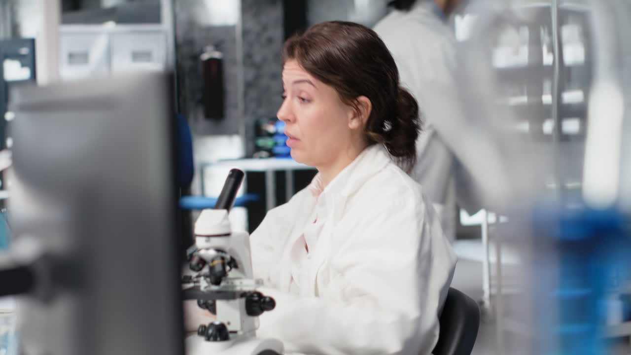 Vertical video Exhausted laboratory molecular biologist stretching at PC desk