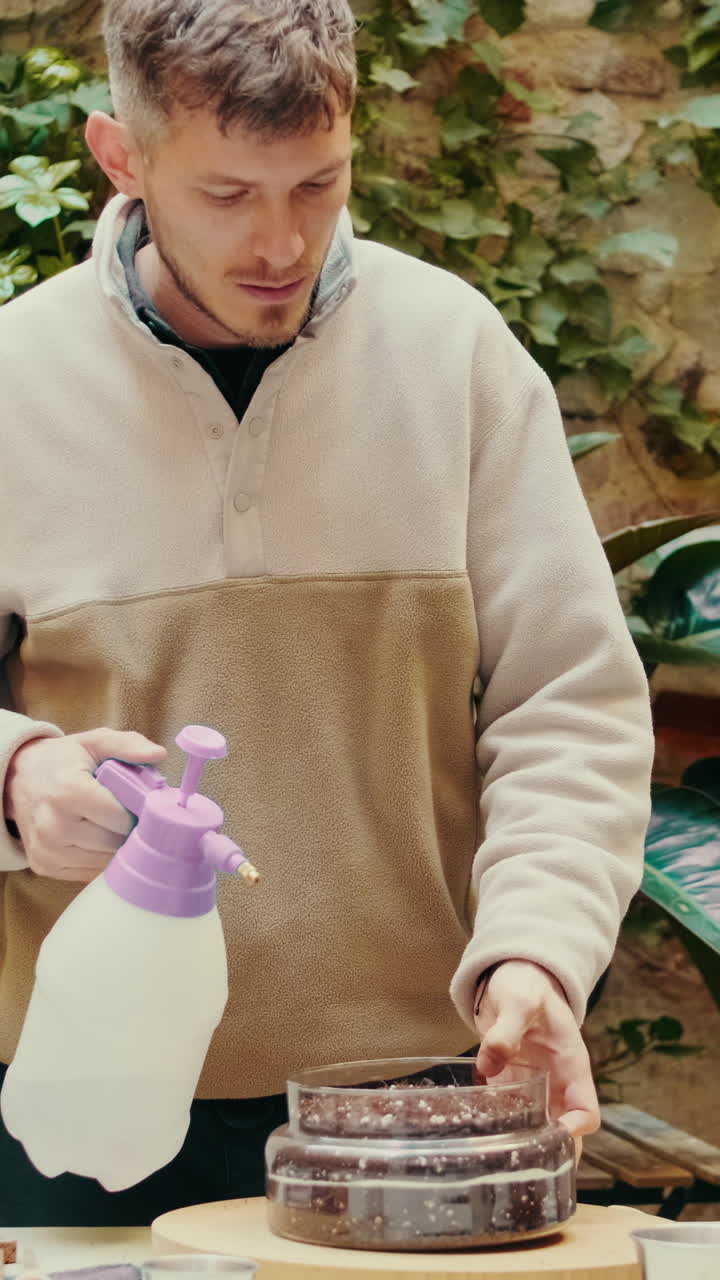 Man Spraying Water on Seeds in a Container for Gardening