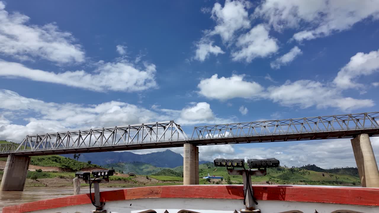 View of a high speed railway bridge spanning the Mekong River in Laos featuring a blue sky with clouds