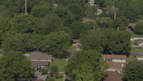 alejamiento aéreo sobre un barrio suburbano con calles, casas, árboles y líneas eléctricas