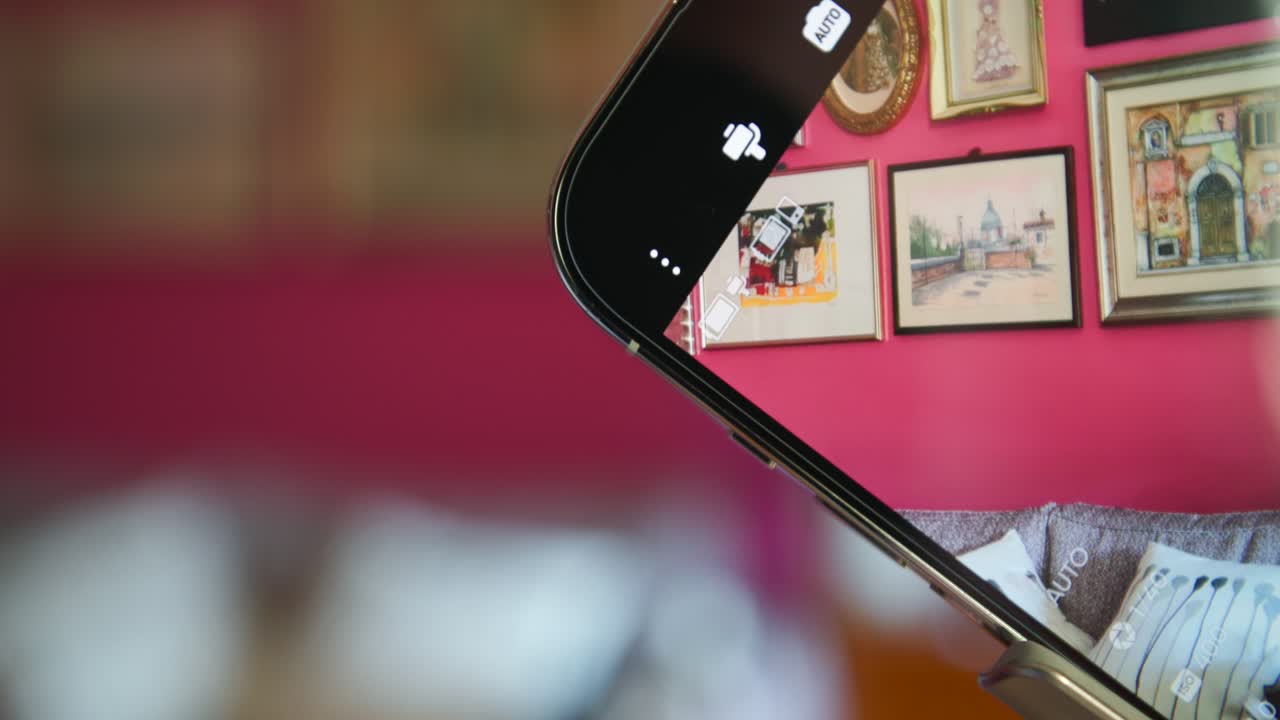 girando el teléfono móvil con la aplicación de fotos marcos activos habitación con pinturas colgando en la pared roja y fondo borroso
