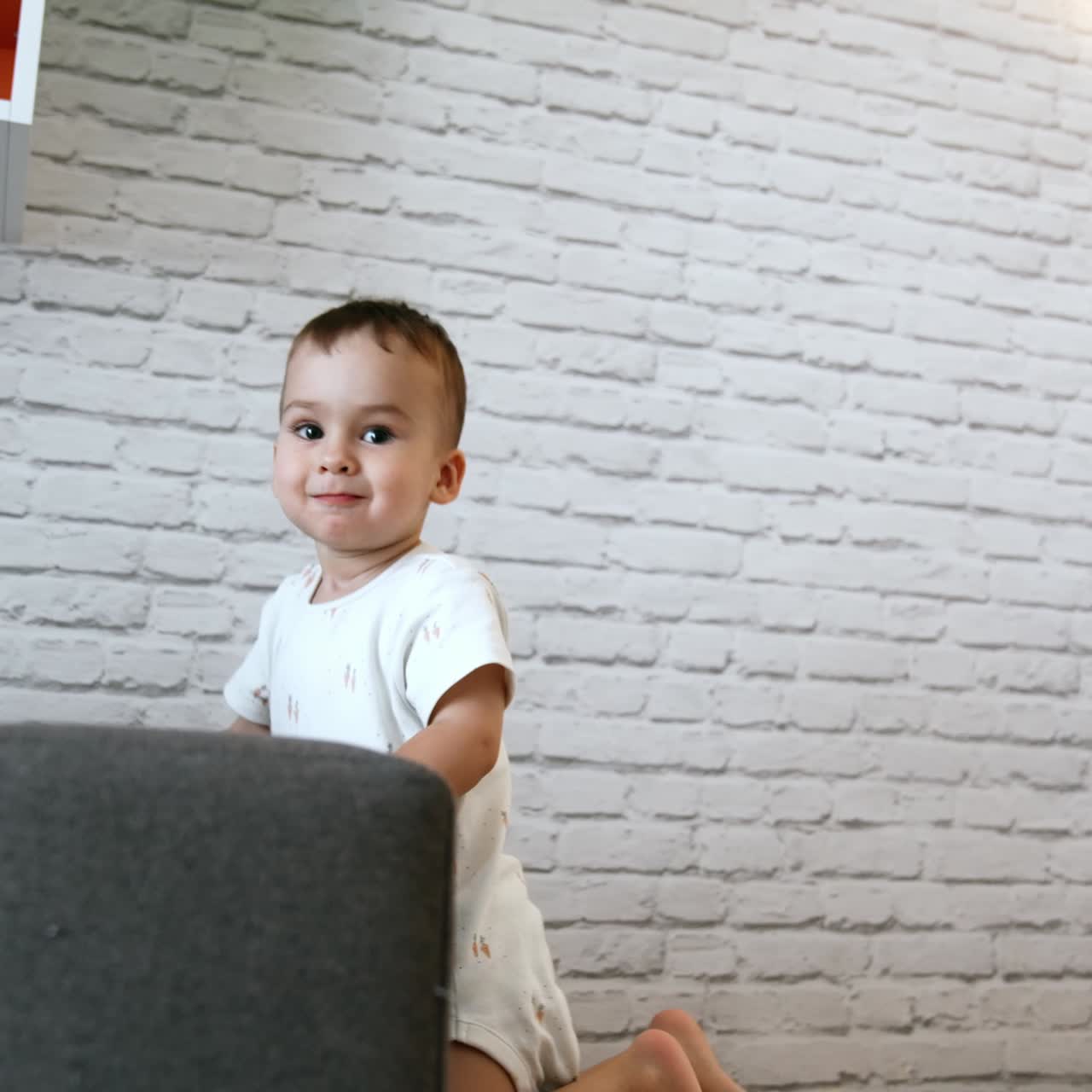 Cute baby boy plays at home. Toddler reaches to get thing he wants from the table