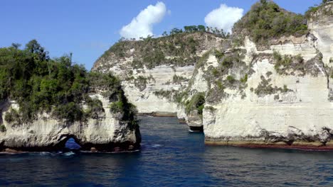 diamond beach in nusa penida island with natural rock arch and tall rock formations, aerial dolly out reveal shot