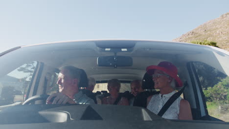 vista desde el exterior del vehículo como un grupo de amigos mayores conducen el coche al destino de vacaciones