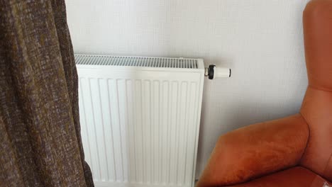 closeup of a white radiator and a brown armchair in a room