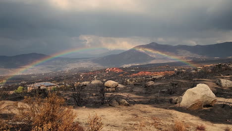 panning view of burned valley with rain and rainbow in the sky