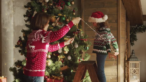 Glückliche-Mutter-Und-Tochter-Tanzen-Und-Spielen-Zusammen-Mit-Lichtern,-Während-Sie-Zu-Hause-Den-Weihnachtsbaum-Schmücken