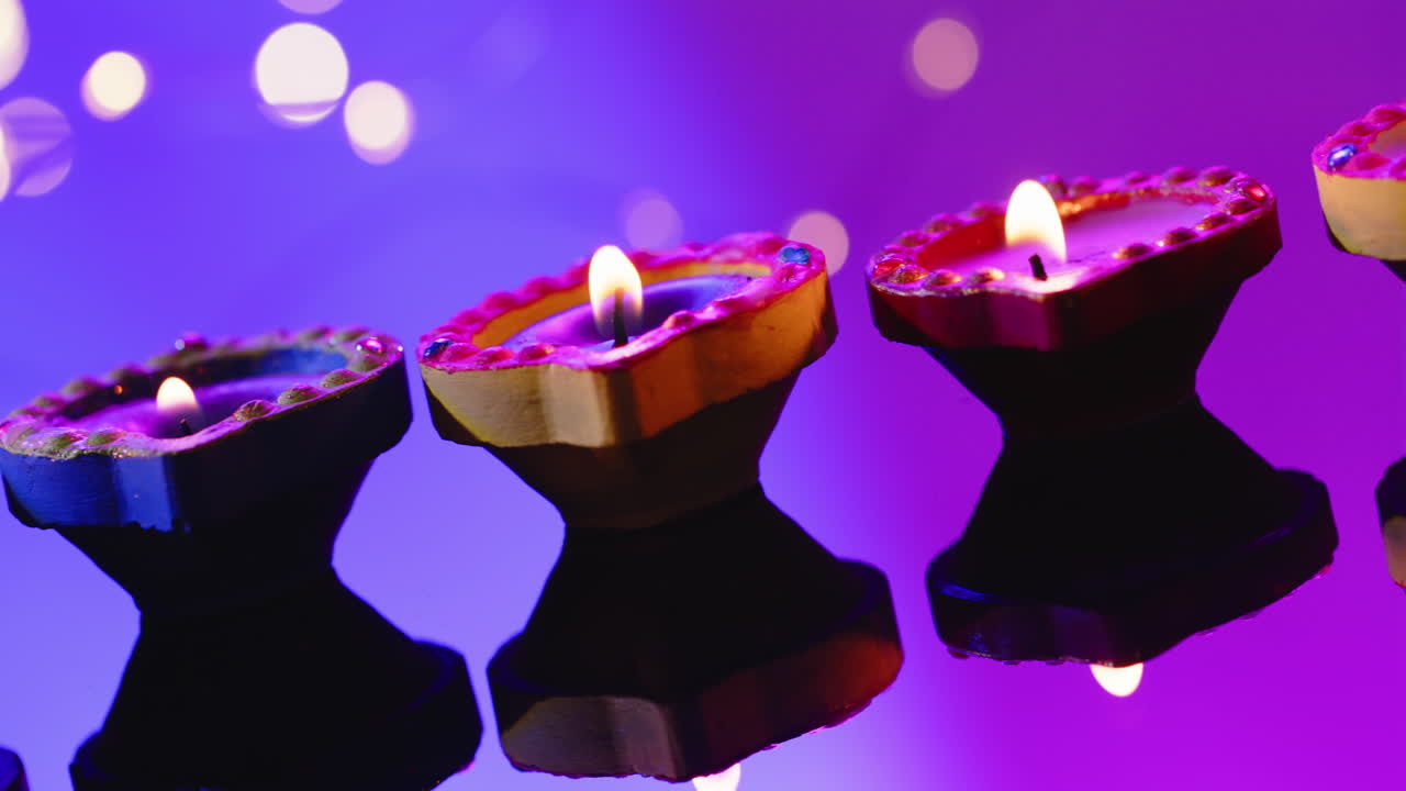 Primo piano di candele accese colorate che celebrano il Diwali su sfondo viola