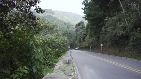 a car traveling alone on a road at the edge of a mountain