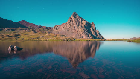 Lapso-De-Tiempo-Del-Pico-Anayet-Y-La-Carpa-Azul-Cerca-Del-Reflejo-Del-Lago-En-Las-Montañas-De-Los-Pirineos-Durante-Una-Noche-De-Luna-Llena,-Aragón,-España