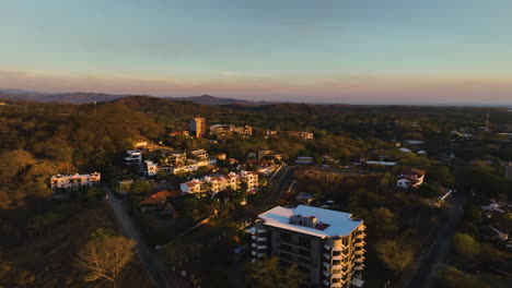 aerial view rising over houses and nature of guanacaste, sunset in costa rica
