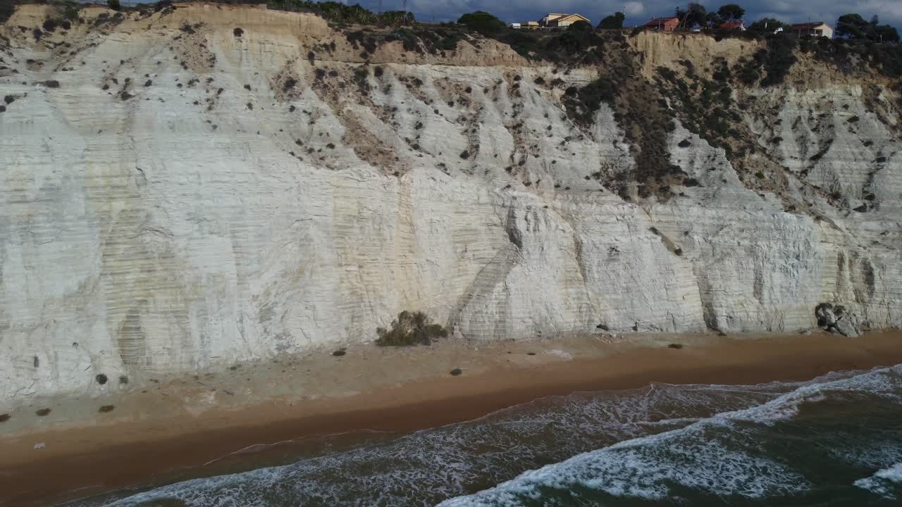 Allontanamento da scogliere bianche e onde su una spiaggia stretta nel Mar Mediterraneo
