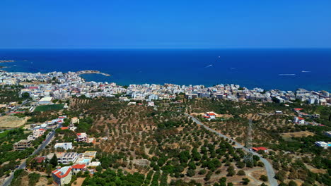 aerial establishing dolly overview of piskopiano, greece, shrubs along hillside down to crowded coast with homes