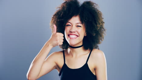 a-young-woman-showing-thumbs-up-against-a-grey