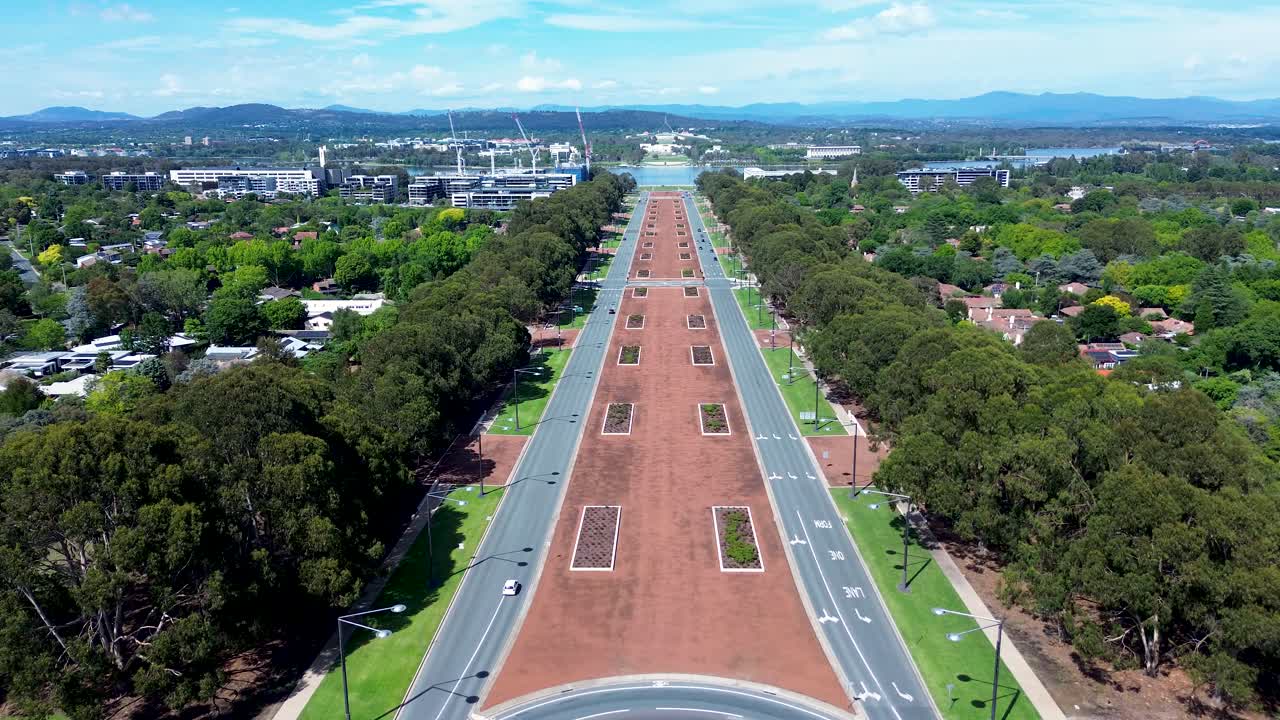 Drone aerial landscape with cars vehicle driving along Anzac Parade boulevard main road street highway in Canberra neighbourhood suburbs ACT Australia travel tourism urban city