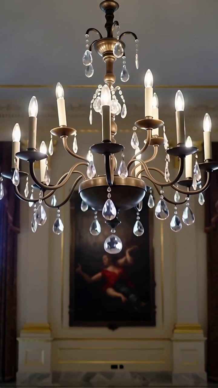 Video verticale: Telecamera che si inclina rivelando un lampadario in ottone in un salone, mostrando pendenti di cristallo.