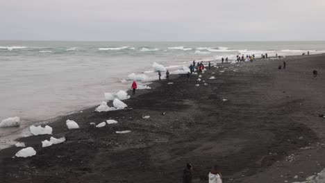 Gletscherlagune-In-Island-Mit-Weitem-Schuss-Von-Menschen-Am-Schwarzen-Sandstrand