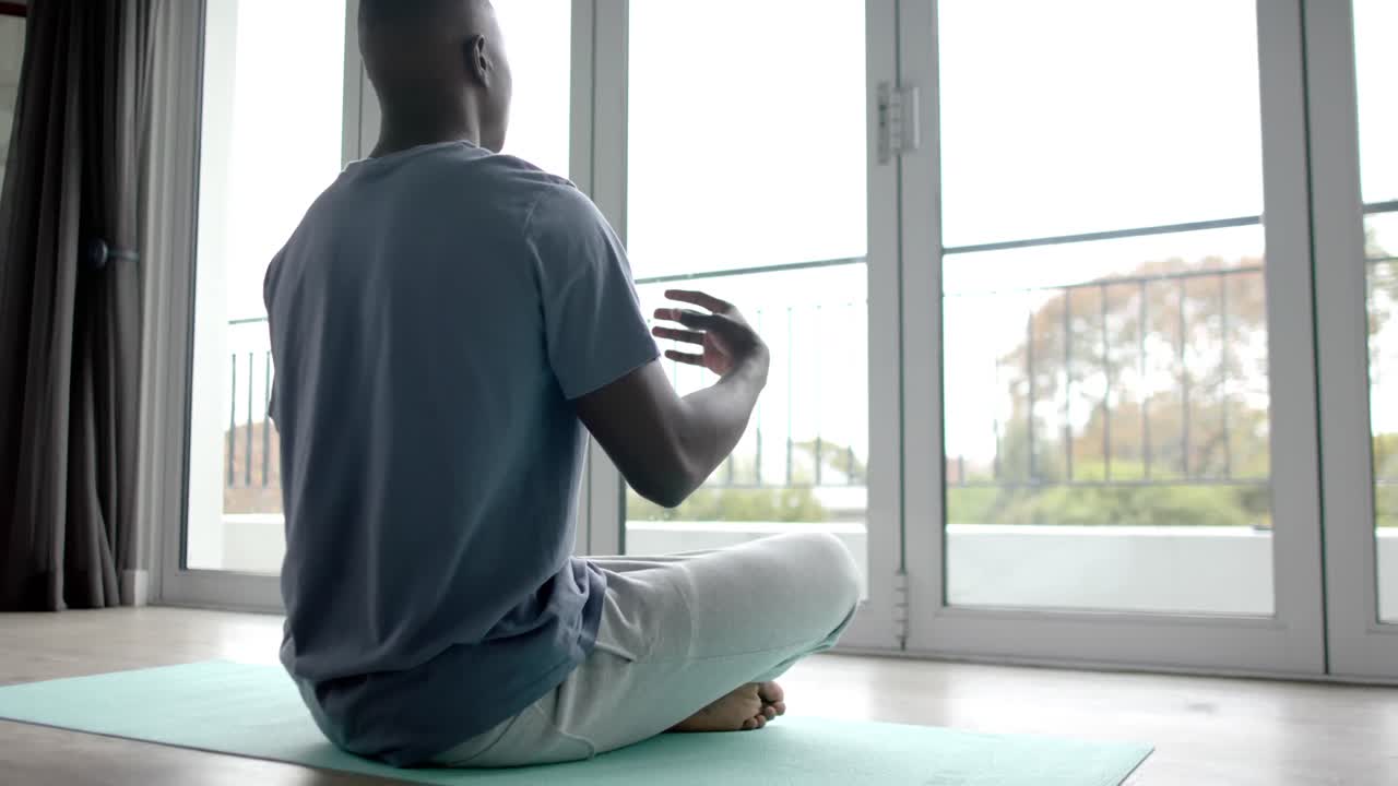 Uomo afroamericano che fa yoga e medita a casa, al rallentatore