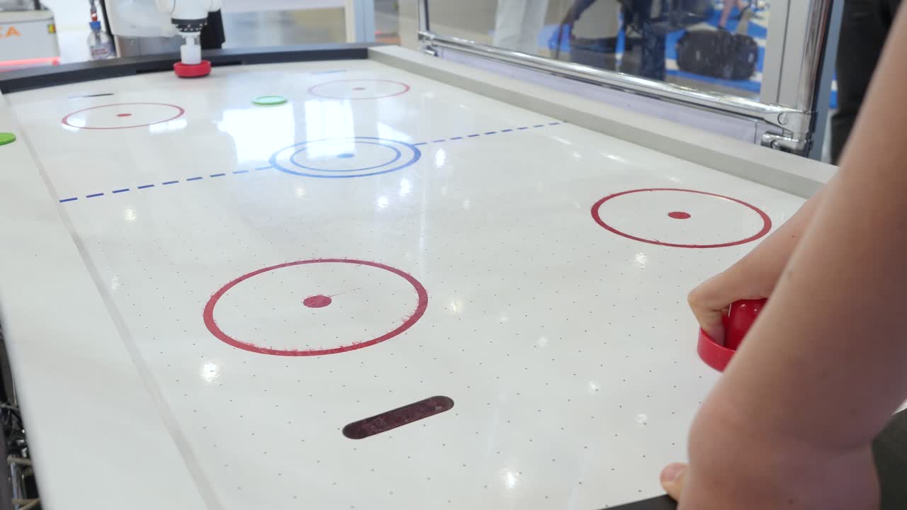 전시회 에서 로 상대 와 함께 에어 하키 를 하는 사람