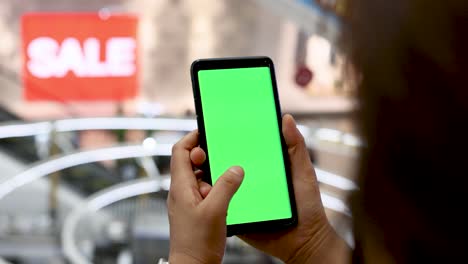 a woman is looking intently at the mobile phone in her hand. green screen mobile phone.