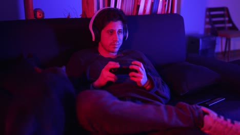 a man in a medium shot plays video games in his apartment