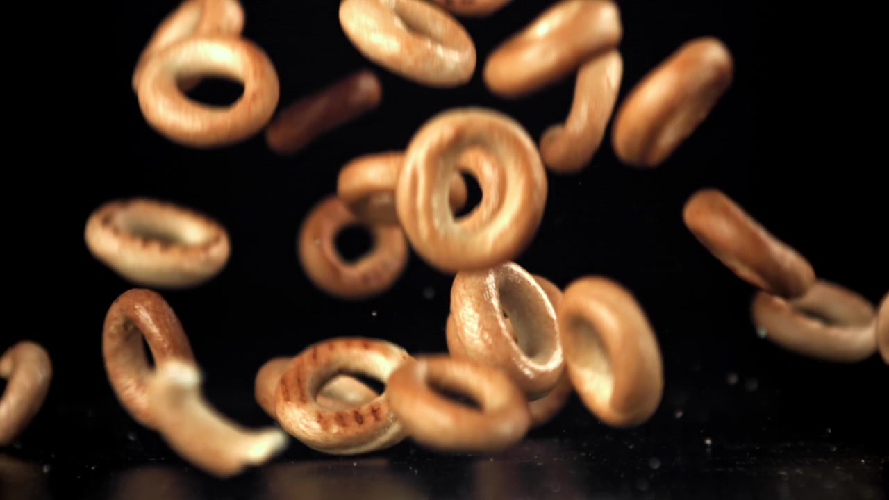 Small Bagels Falling in Slow Motion on Black Background