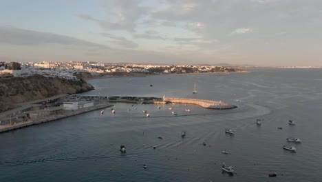 aerial view of boat leaving harbor during sunset. view over ocean with beach and town in the distance